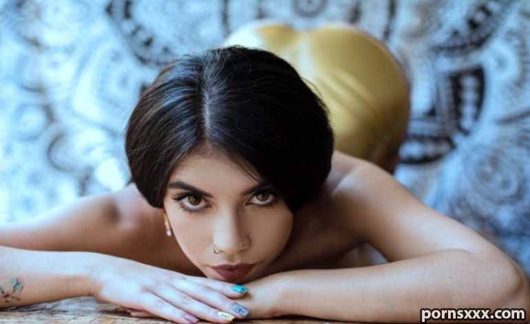 How To Choose The Best Adult Nightly Companion For Your Needs Woman with dark hair lying on her stomach, arms crossed under her chin, gazing at the camera with a patterned blue background behind her.